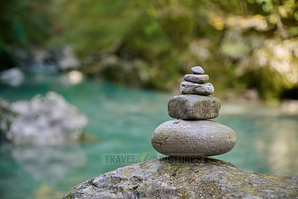 Balanced pebble pyramid stones with a blurred river in the background