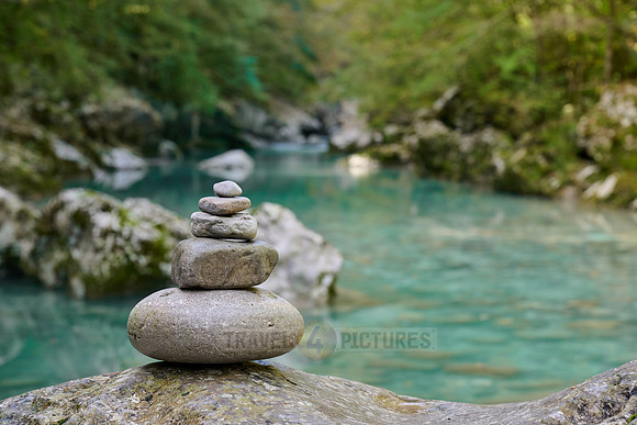 Balanced pebble pyramid stones with a blurred river in the background