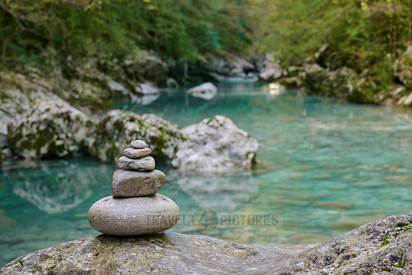 Balanced pebble pyramid stones with a blurred river in the background