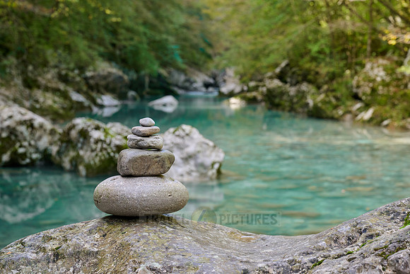 Balanced pebble pyramid stones with a blurred river in the background