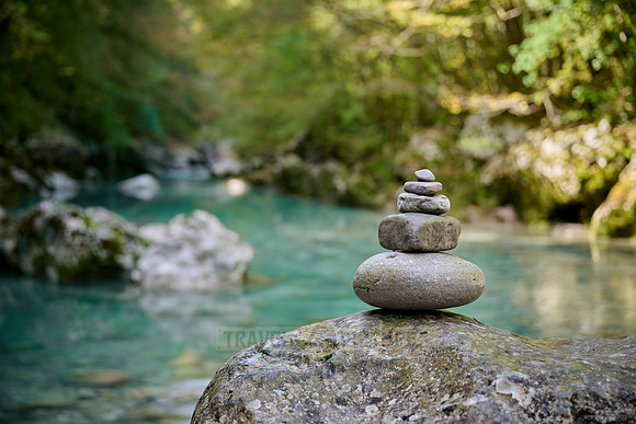 Balanced pebble pyramid stones with a blurred river in the background