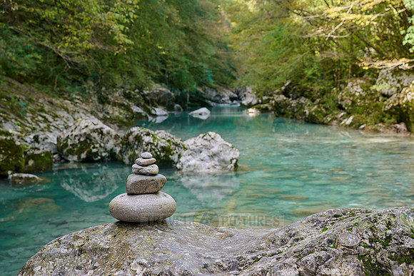 Balanced pebble pyramid stones with a blurred river in the background