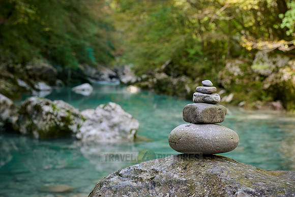 Balanced pebble pyramid stones with a blurred river in the background