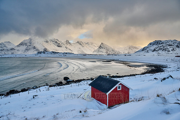 red hut in winter landscape with sea and mountains at Sandbotnen, Lofoten,