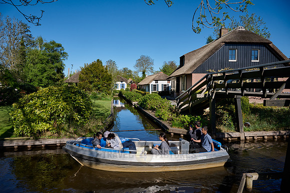 tourists in boat on canal and traditional house in dutch Giethoorn village