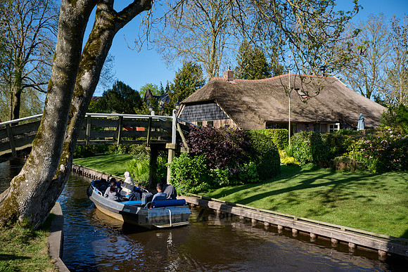 tourists in boat on canal and traditional house in dutch Giethoorn village