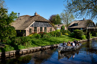 tourists in boat on canal and traditional house in dutch Giethoorn village