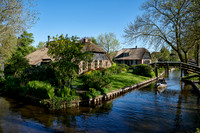 tourists in boat on canal and traditional house in dutch Giethoorn village
