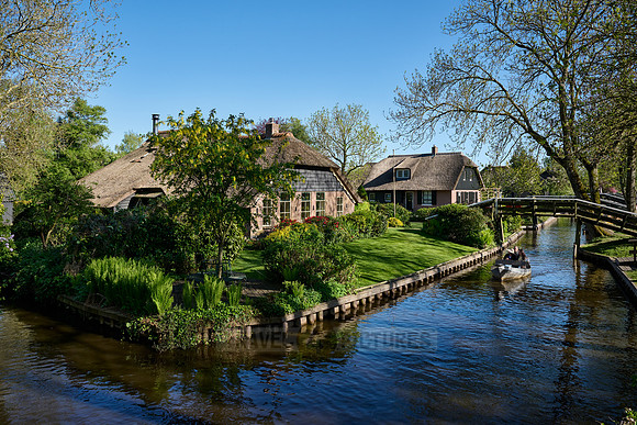 tourists in boat on canal and traditional house in dutch Giethoorn village