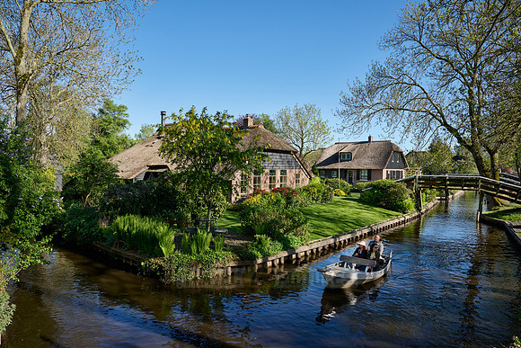 tourists in boat on canal and traditional house in dutch Giethoorn village