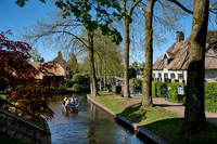 tourists in boat on canal and traditional house in dutch Giethoorn village
