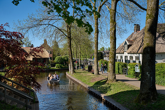 tourists in boat on canal and traditional house in dutch Giethoorn village
