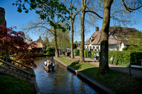tourists in boat on canal and traditional house in dutch Giethoorn village