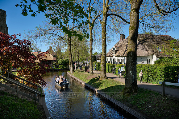 tourists in boat on canal and traditional house in dutch Giethoorn village