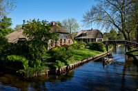 tourists in boat on canal and traditional house in dutch Giethoorn village