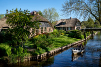 tourists in boat on canal and traditional house in dutch Giethoorn village