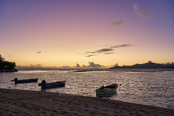 small boats during sunset on sea of La Digue