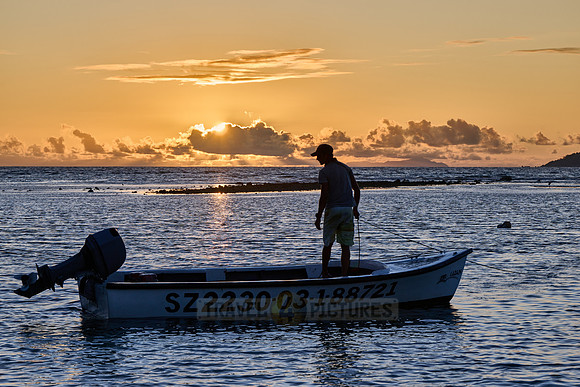 fisherman on his boat while sunset, La Digue