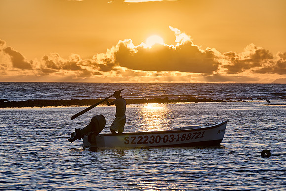 fisherman on his boat while sunset, La Digue