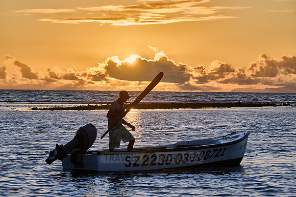 fisherman on his boat while sunset, La Digue