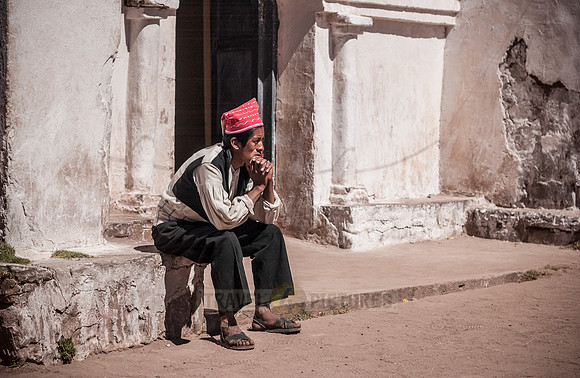 local man in traditional cloth sitting in front of church on Isla Taquile