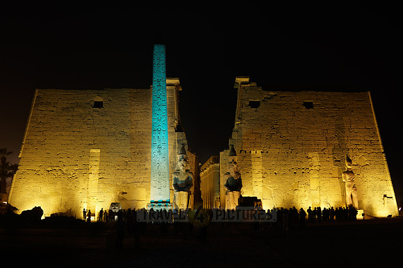 night shot of illuminated statues and obelisk of Ramesses II. in front of first Pylon