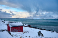 red hut in winter landscape with sea and mountains at Sandbotnen, Lofoten,