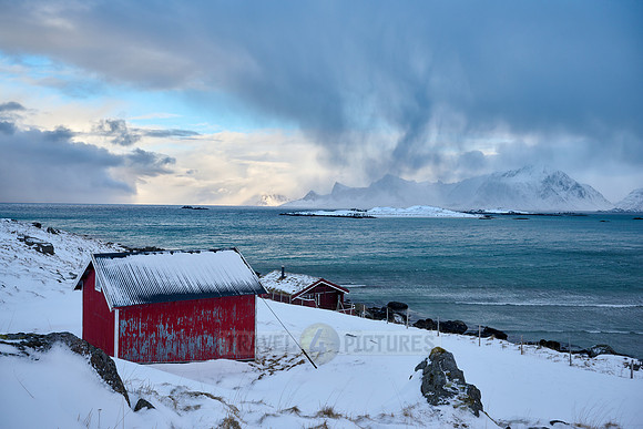 red hut in winter landscape with sea and mountains at Sandbotnen, Lofoten,