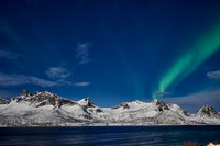Aurora Borealis over winter landscape in fjord of Husøy