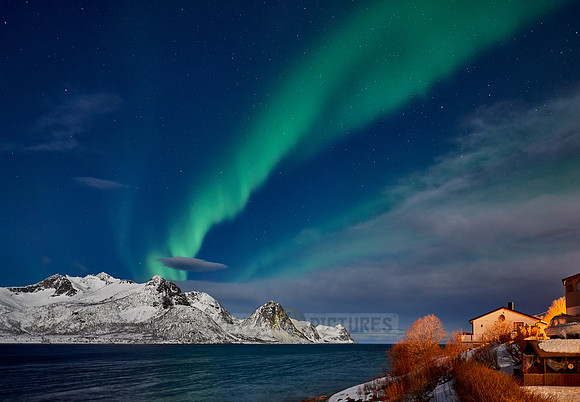 Aurora Borealis over winter landscape in fjord of Husøy