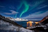 Aurora Borealis over winter landscape in fjord of Husøy