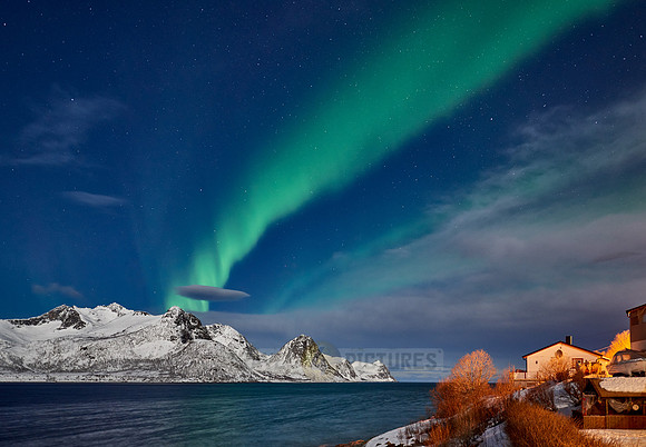 Aurora Borealis over winter landscape in fjord of Husøy