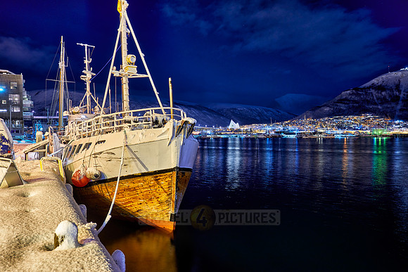night shot of a snow covered vessel in harbor of Tromsø