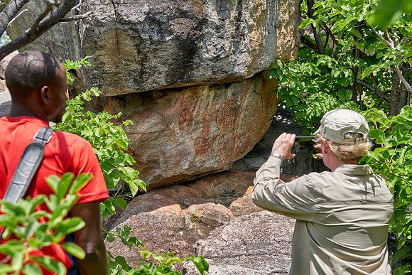 tourist and guide looking on Rock art