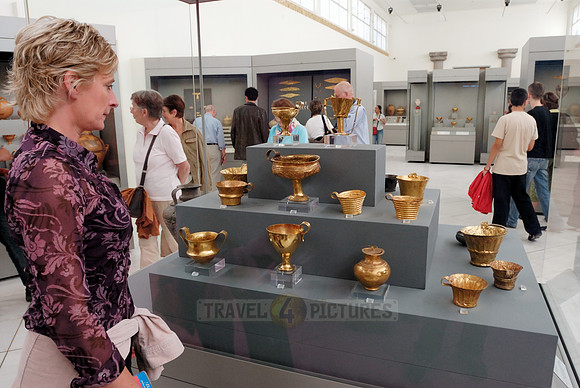 Visitor looks at gold vessels in a showcase