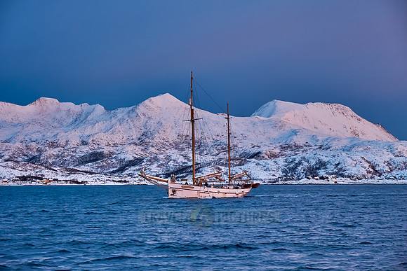 sunrise over fjord with winter landscape and sail ship