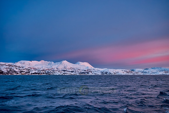 sunrise over fjord with winter landscape seen from sail ship
