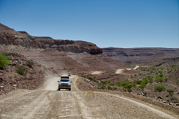 4x4 cars on deserted gravel road in desert landscape