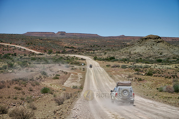 4x4 cars on deserted gravel road in desert landscape