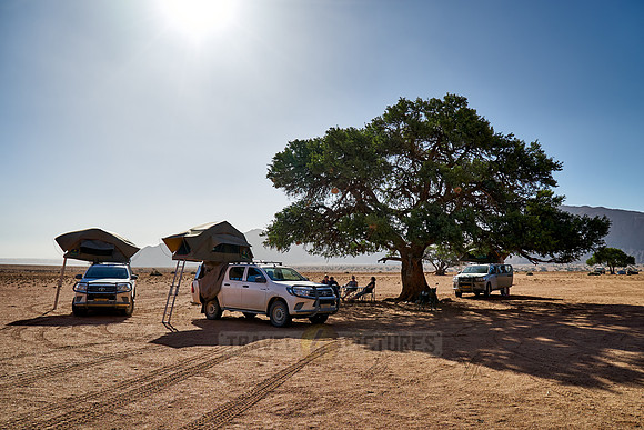 tourists in self-drive 4x4 car camping in desert landscape