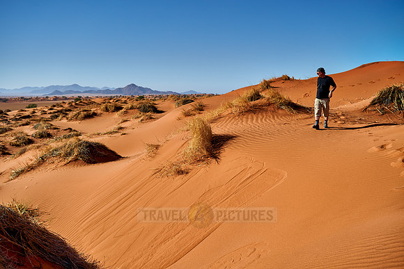 man is walking through deserted landscape of NamibRand Nature Reserve
