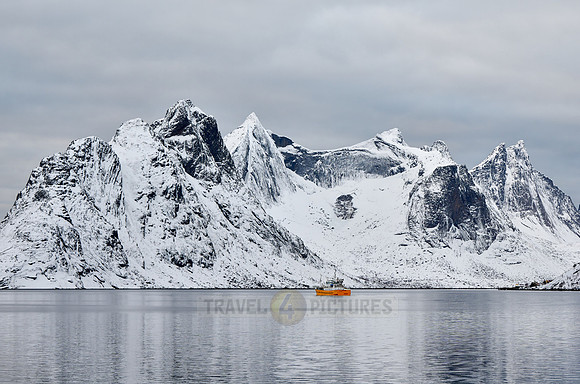 yellow vessel in front of spectacular winter landscape in the bay of Hamnoy