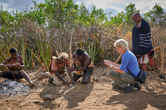 tourist watching bushmen making fire