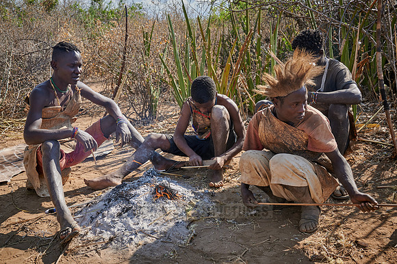 bushmen of Hasabe tribe sitting around a fireplace
