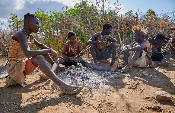 bushmen of Hasabe tribe sitting around a fireplace