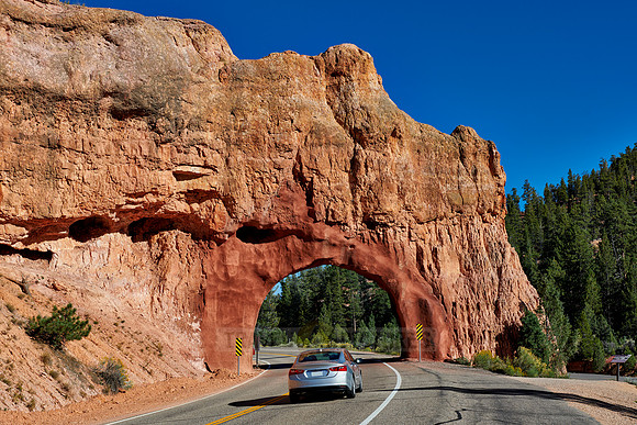 car on road through arch in Red Canyon