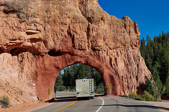 Camper on road through arch in Red Canyon