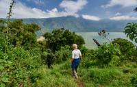 Tourist and Ranger walking through forest down to Lake Empakaai