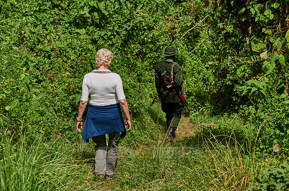 Tourist and Ranger walking through forest down to Lake Empakaai