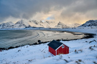 red hut in winter landscape with sea and mountains at Sandbotnen, Lofoten,
